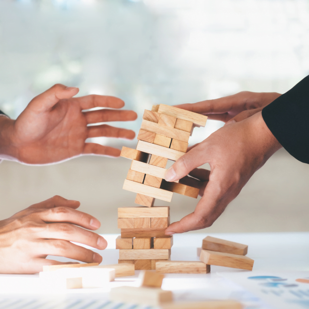 Picture of two hands playing Jenga to represent risk in a business and how risk management simulations and risk management training helps.